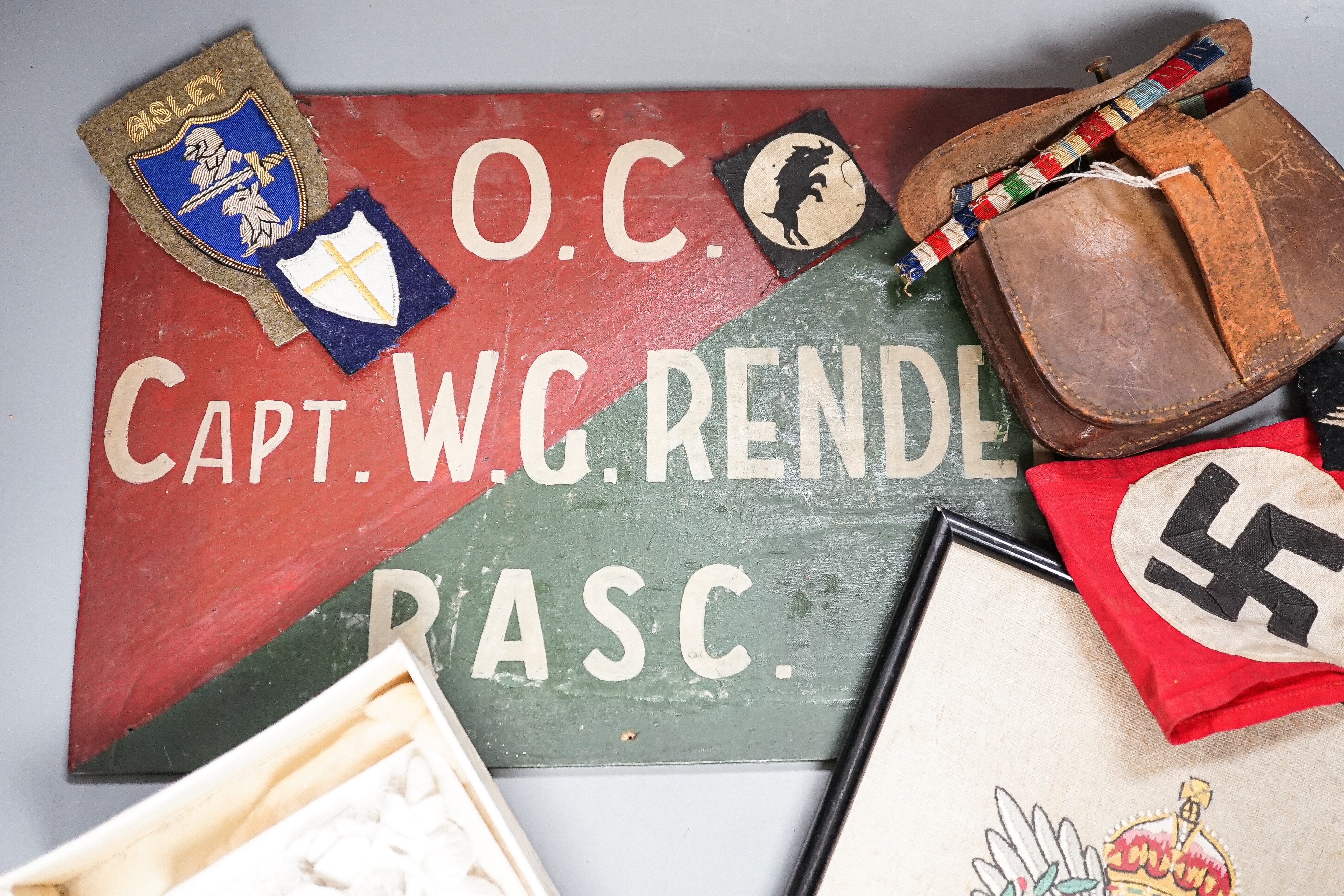 A group of WWI and WWII militaria badges, buttons, two swagger sticks, an armband and a World War I German POW inscribed plaster ornament, longest swagger stick 70 cms long.